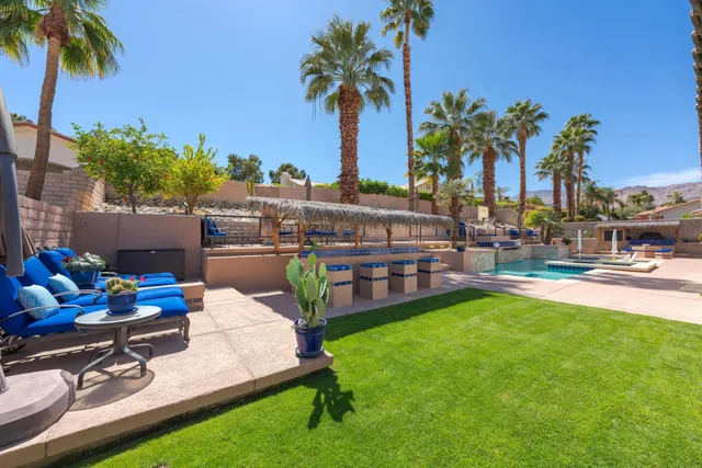 a view of a patio with couches table and chairs under an umbrella
