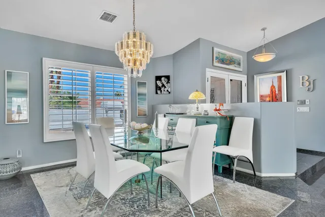 a dining room with stainless steel appliances granite countertop a table chairs and a refrigerator