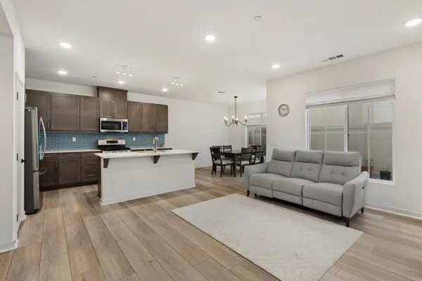 a living room kitchen with stainless steel appliances granite countertop a couch and a view of living room