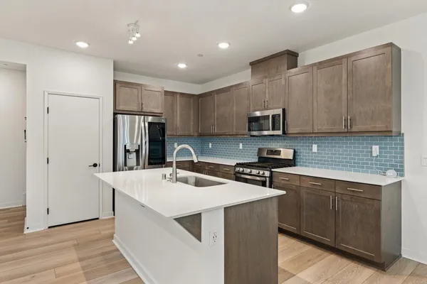 a kitchen with stainless steel appliances granite countertop a sink stove microwave and refrigerator