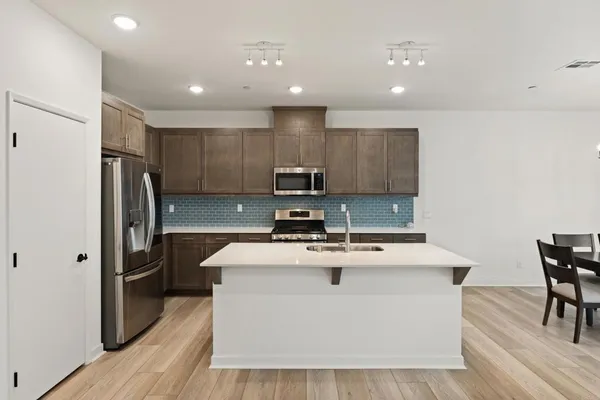 a kitchen with kitchen island a sink appliances and wooden floor