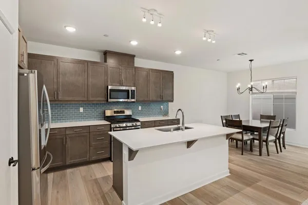 a kitchen that has a lot of cabinets in it and stainless steel appliances