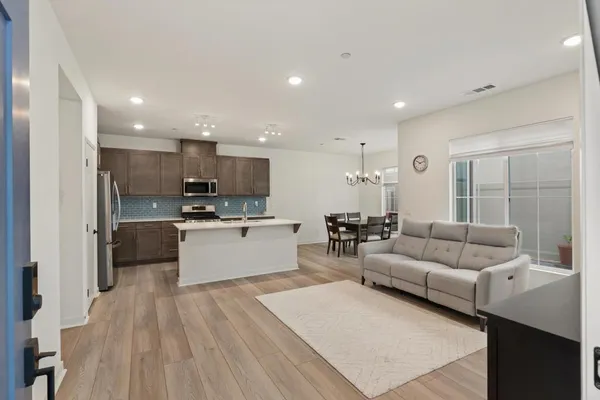 a living room kitchen with stainless steel appliances kitchen island granite countertop a couch and a view of living room