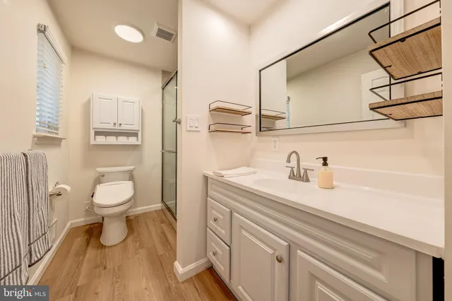 a bathroom with a granite countertop sink toilet a mirror and shower
