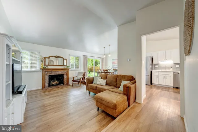a living room with furniture a fireplace and a kitchen view with wooden floor