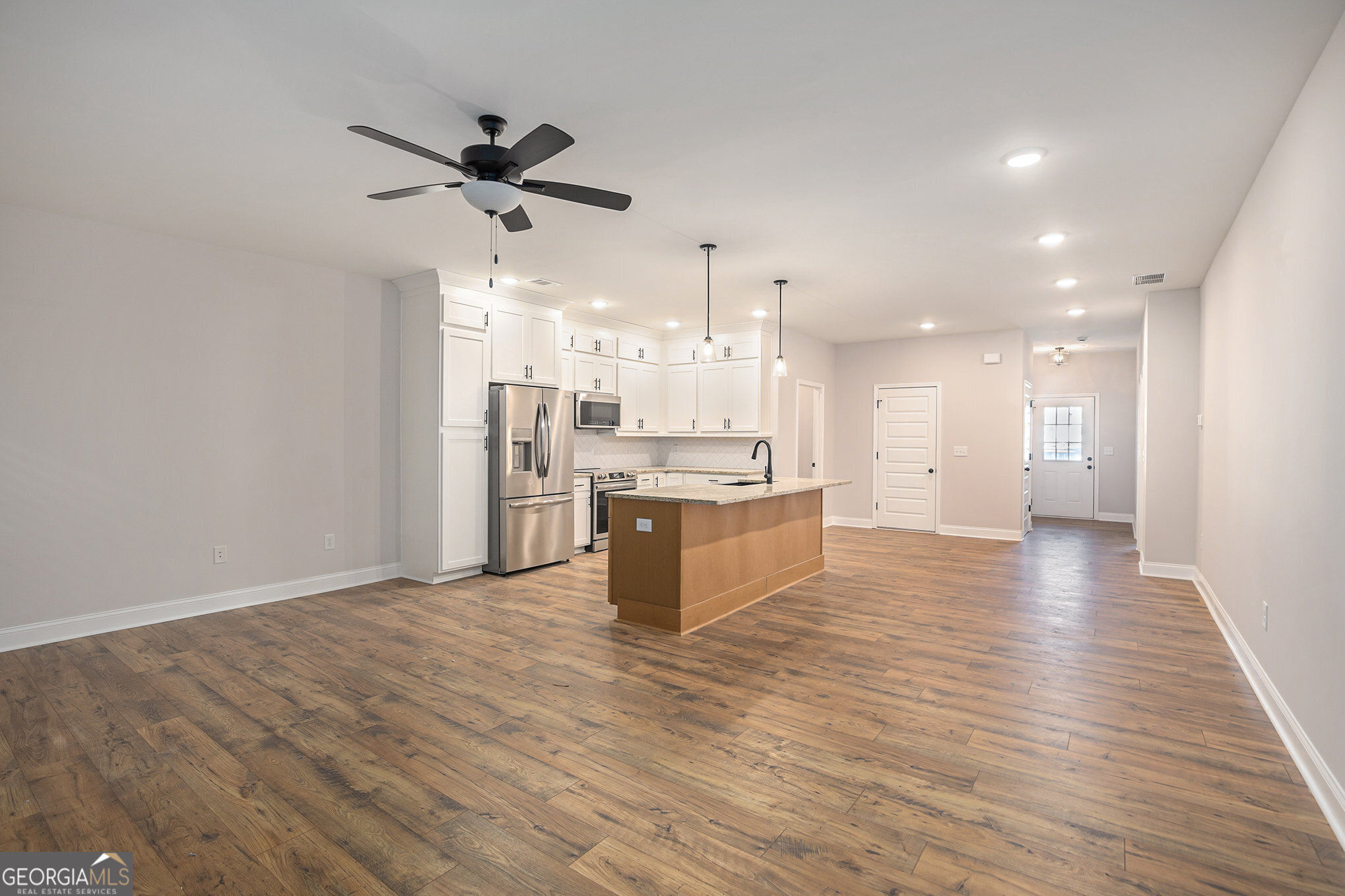 138 Crest Pointe Bremen, GA 30110 - Photo 4 of 22 a view of a kitchen with kitchen island a sink wooden floor and a refrigerator