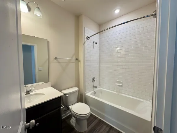 a bathroom with a bathtub shower sink vanity mirror and toilet