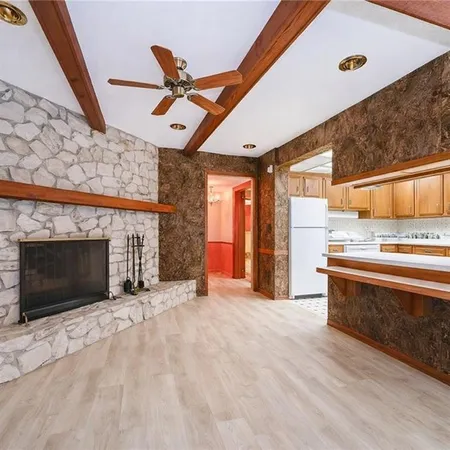 a view of empty room with kitchen and fireplace