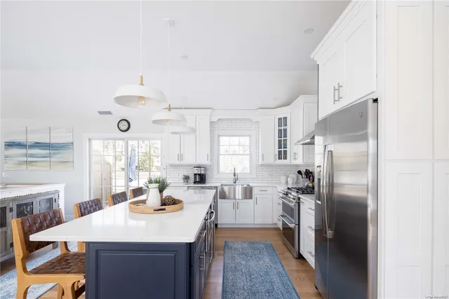 a kitchen with stainless steel appliances a refrigerator a sink dishwasher a oven with white cabinets and wooden floor