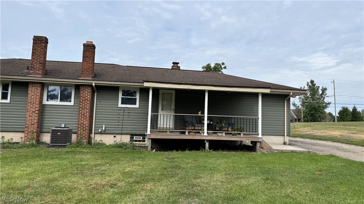 11784 Chamberlain Road Mantua, OH 44255 - Photo 44 of 50 Rear exterior featuring green siding, two brick chimneys, a covered porch with white railings, and a gravel driveway