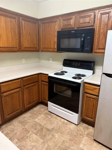 a kitchen with granite countertop a stove top oven microwave and cabinets
