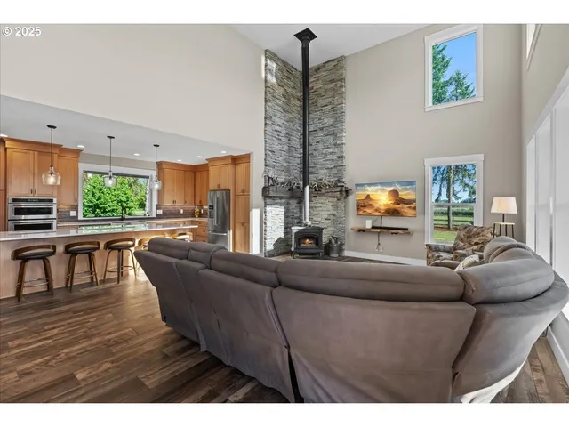 a open kitchen with stainless steel appliances kitchen island granite countertop a sink dishwasher a stove and a refrigerator with wooden floor