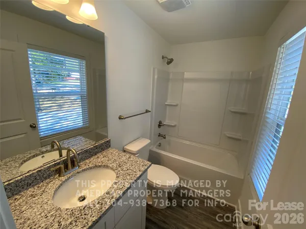 a bathroom with a granite countertop sink a mirror and a bathtub