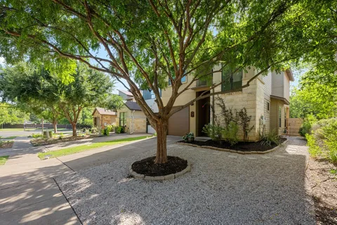 a front view of a house with garden and trees