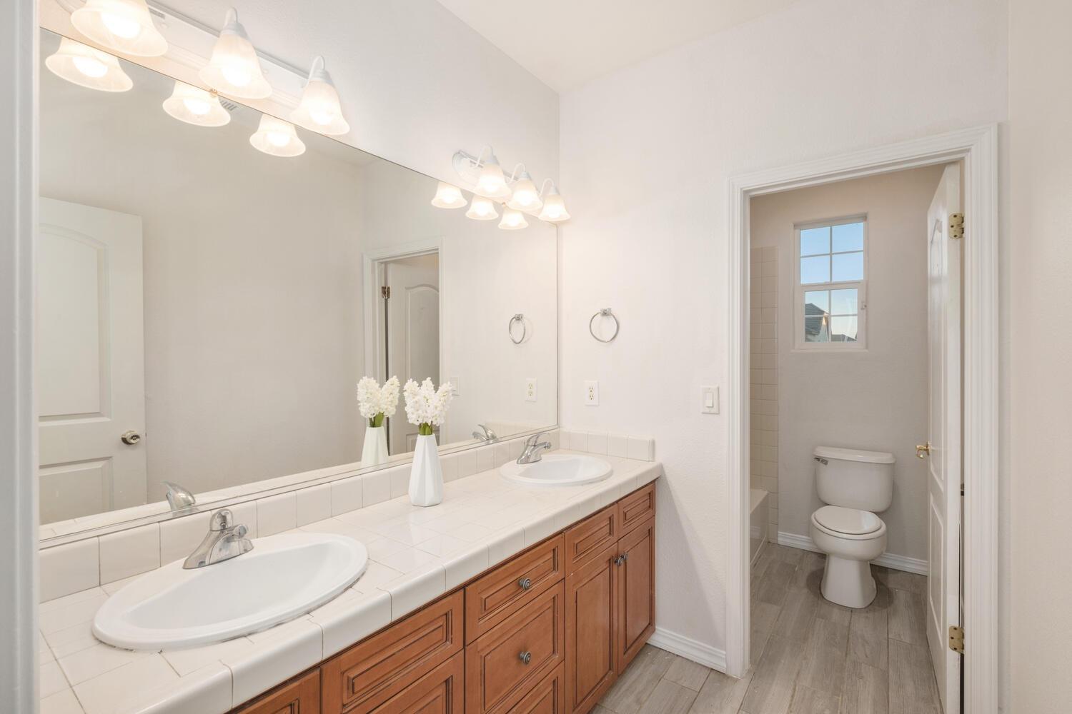 3331 Serena Avenue Clovis, CA 93619 - Photo 31 of 41 a bathroom with a sink a toilet and a large mirror