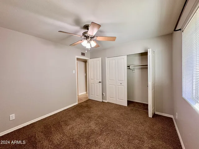 an empty room with a chandelier fan and windows
