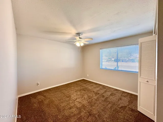 an empty room with closet and a ceiling fan