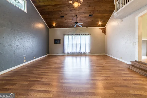 a view of a hallway with wooden floor and a bathroom