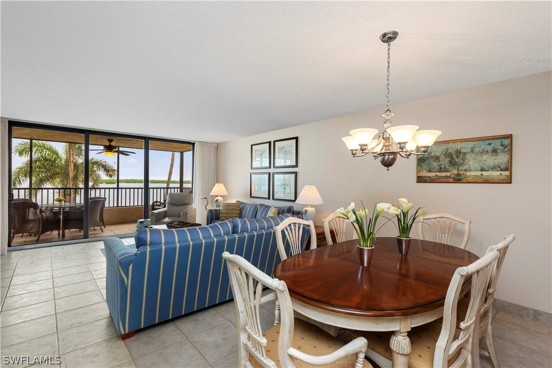 15021 Punta Rassa Road, Unit 201 Fort Myers, FL 33908 - Photo 12 of 29 a view of a dining room with furniture a chandelier and large windows