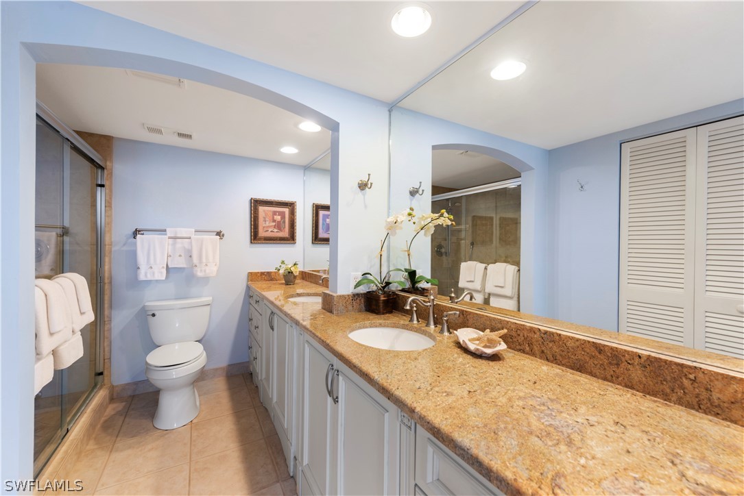 15021 Punta Rassa Road, Unit 201 Fort Myers, FL 33908 - Photo 7 of 29 a bathroom with a granite countertop sink a toilet a mirror and shower