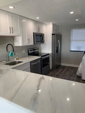 a kitchen with stainless steel appliances a sink a stove a refrigerator cabinets and a counter top space