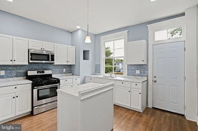 a kitchen with a sink white cabinets and stainless steel appliances