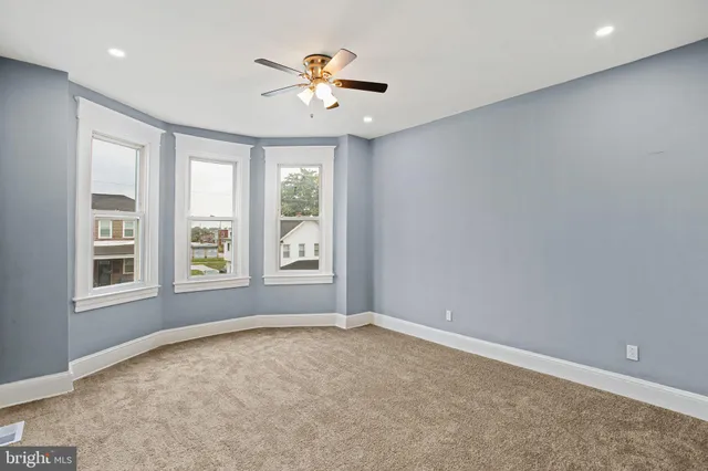 an empty room with windows and chandelier fan