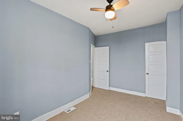 an empty room with ceiling fan and window