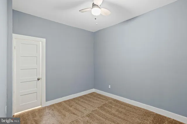 an empty room with a ceiling fan and carpet