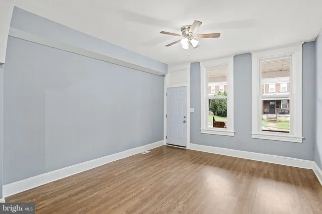a view of an empty room with a window and wooden floor