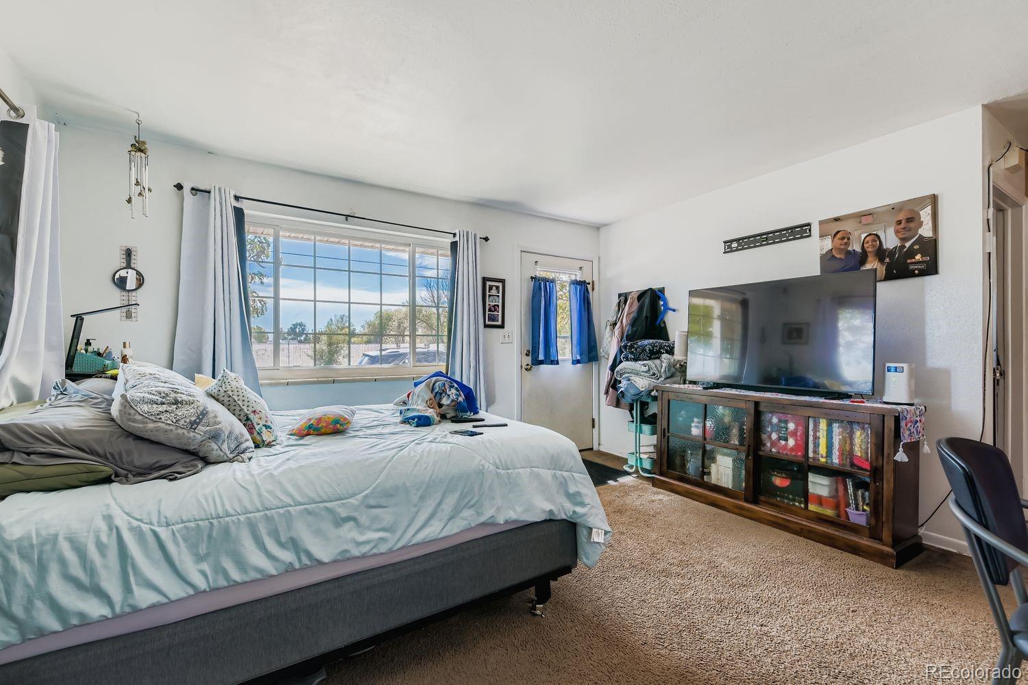315 6th Street Fort Lupton, CO 80621 - Photo 8 of 26 a bedroom with a bed window and a flat screen tv
