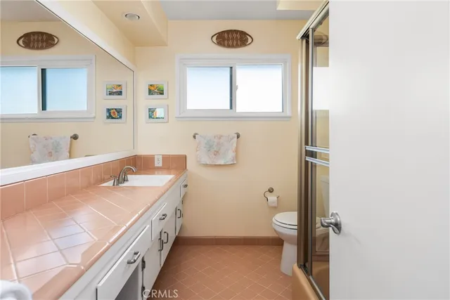 a bathroom with a granite countertop sink a large mirror and a toilet