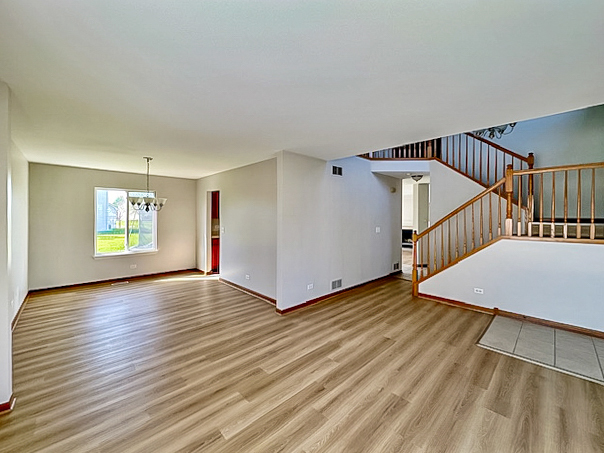637 Deames Street Plano, IL 60545 - Photo 3 of 18 a view of an empty room with wooden floor and a window