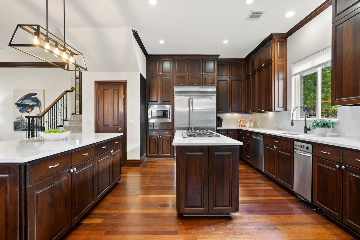 12027 Pleasant Panorama View Austin, TX 78738 - Photo 15 of 40 a kitchen with stainless steel appliances granite countertop wooden cabinets a sink and dishwasher a refrigerator with wooden floor