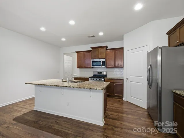 a kitchen with granite countertop a refrigerator stove top oven and sink