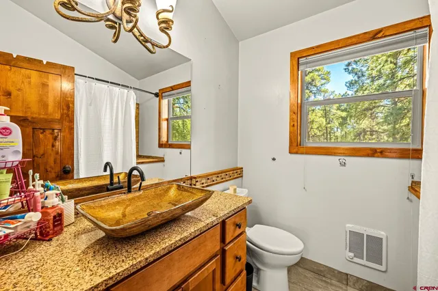 a bathroom with a granite countertop sink and a toilet