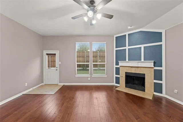 a view of an empty room with wooden floor fireplace and a window