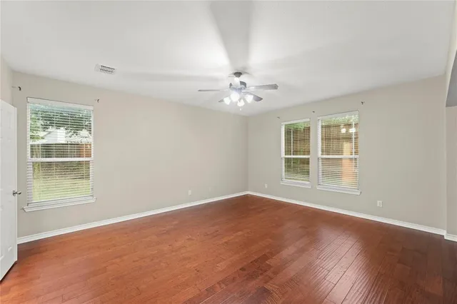 a view of an empty room with a window and wooden floor
