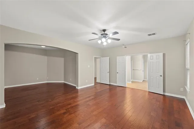 a view of an empty room with a window and wooden floor