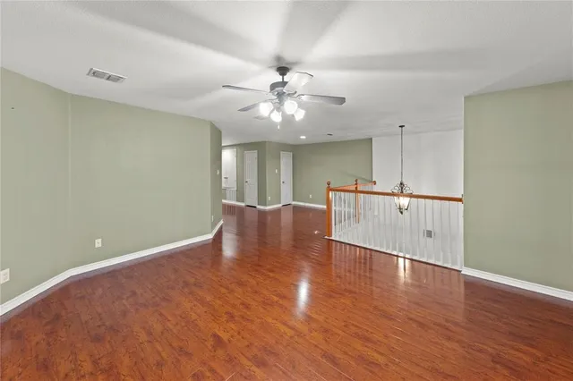 an empty room with wooden floor and a ceiling fan