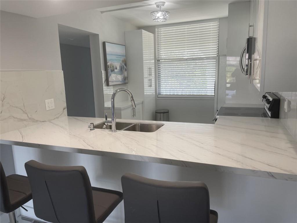 1721 Whitehall Drive, Unit 404 Davie, FL 33324 - Photo 3 of 16 a bathroom with a granite countertop sink a toilet and a large mirror