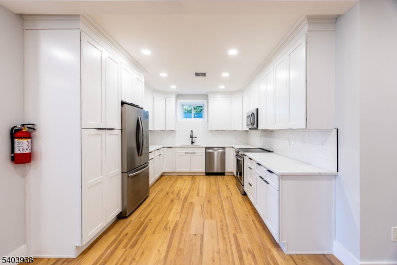24 Bertrand Island Road Mount Arlington, NJ 07856 - Photo 14 of 44 a large kitchen with a refrigerator a sink dishwasher and a stove top oven with wooden floor