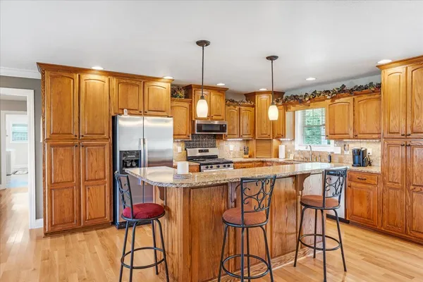 a kitchen with stainless steel appliances granite countertop a stove a refrigerator a sink dishwasher and white cabinets with wooden floor