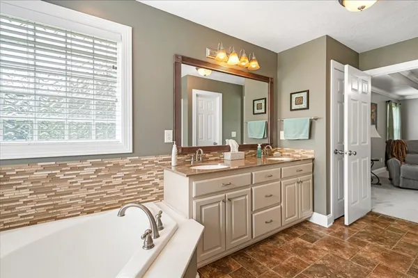 a spacious bathroom with a tub sink and mirror