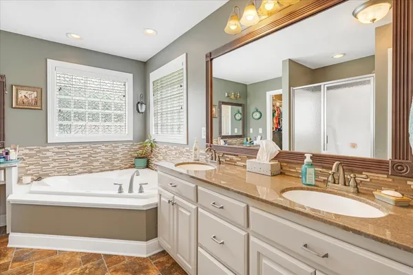 a bathroom with a granite countertop tub sink and mirror
