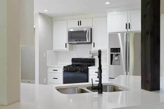 a open kitchen with white cabinets and wooden floor