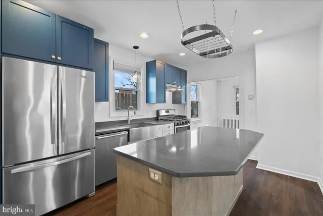 a kitchen with stainless steel appliances granite countertop a refrigerator a sink dishwasher a refrigerator white cabinets and wooden floor