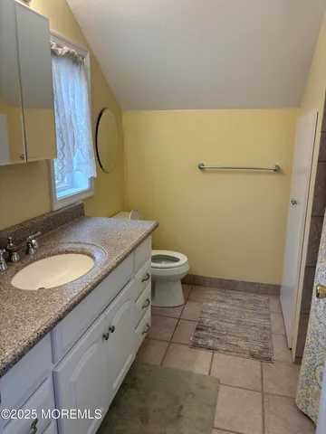 a bathroom with a granite countertop toilet sink and mirror