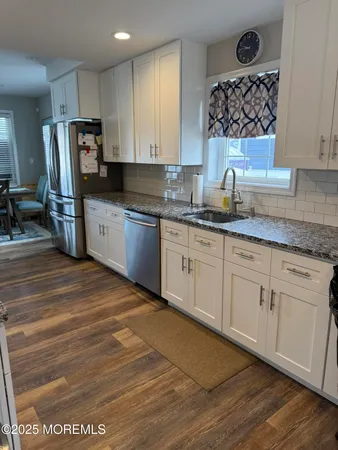a kitchen with stainless steel appliances granite countertop a sink stove refrigerator and cabinets