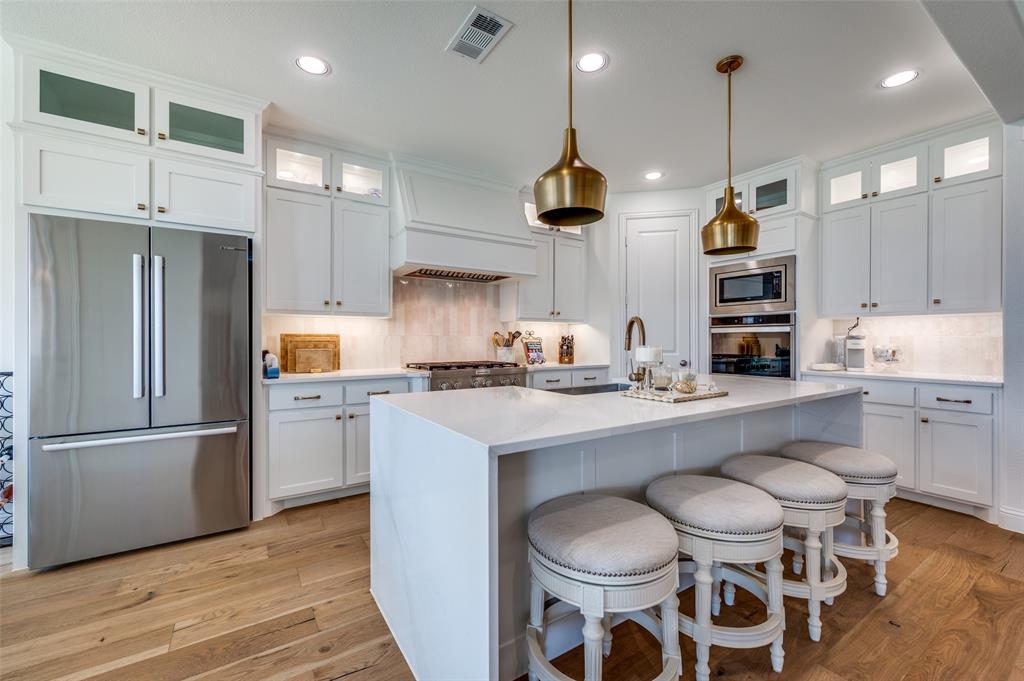 2390 Red Cedar Trail Prosper, TX 75078 - Photo 11 of 40 a kitchen with stainless steel appliances a sink a stove a refrigerator and chairs
